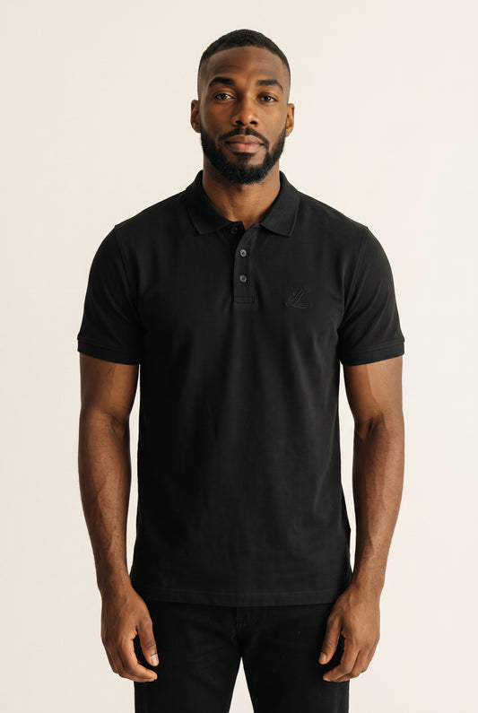 Male model wearing a black organic cotton polo shirt with tonal Legacy chest embroidery.