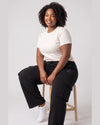 Woman seated wearing black Legacy heavyweight organic cotton cargo pants with thigh flap pockets.