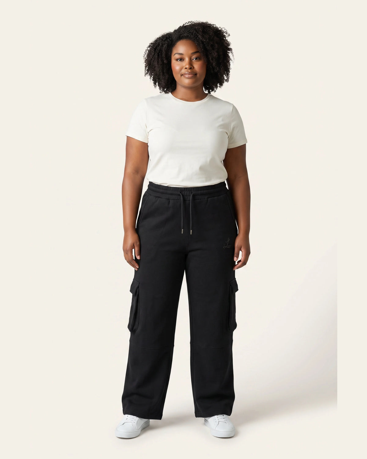 Front view of woman wearing black Legacy 450 GSM cargo pants with elastic drawcord waist and utility pockets.