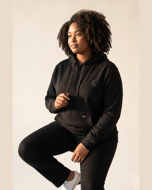Woman wearing Legacy black heavyweight organic cotton hoodie with natural hair.