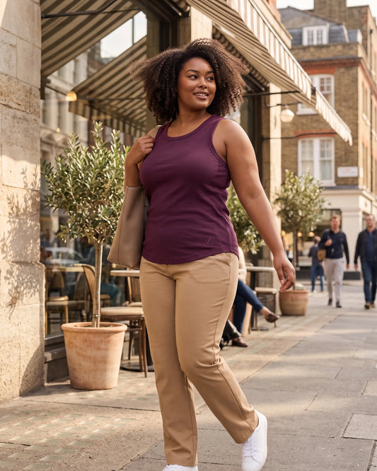 Woman walking outdoors in the Legacy deep plum ribbed tank styled with beige trousers.